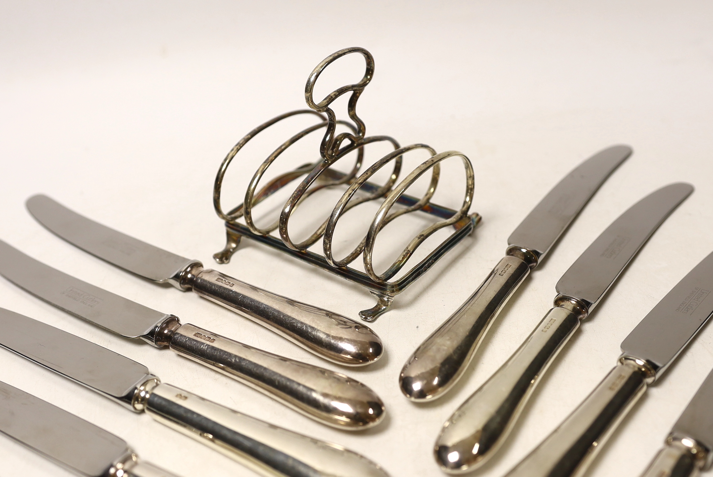 A set of six modern silver handled table knives and dessert knives, United Cutlers, Sheffield, 1997/8, a small silver five bar toast rack, two silver forks, a silver spoon and a pair of silver plated sugar tongs.